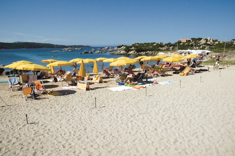 Písečná pláž se slunečníky, Golfo di Marinella, Sardinie